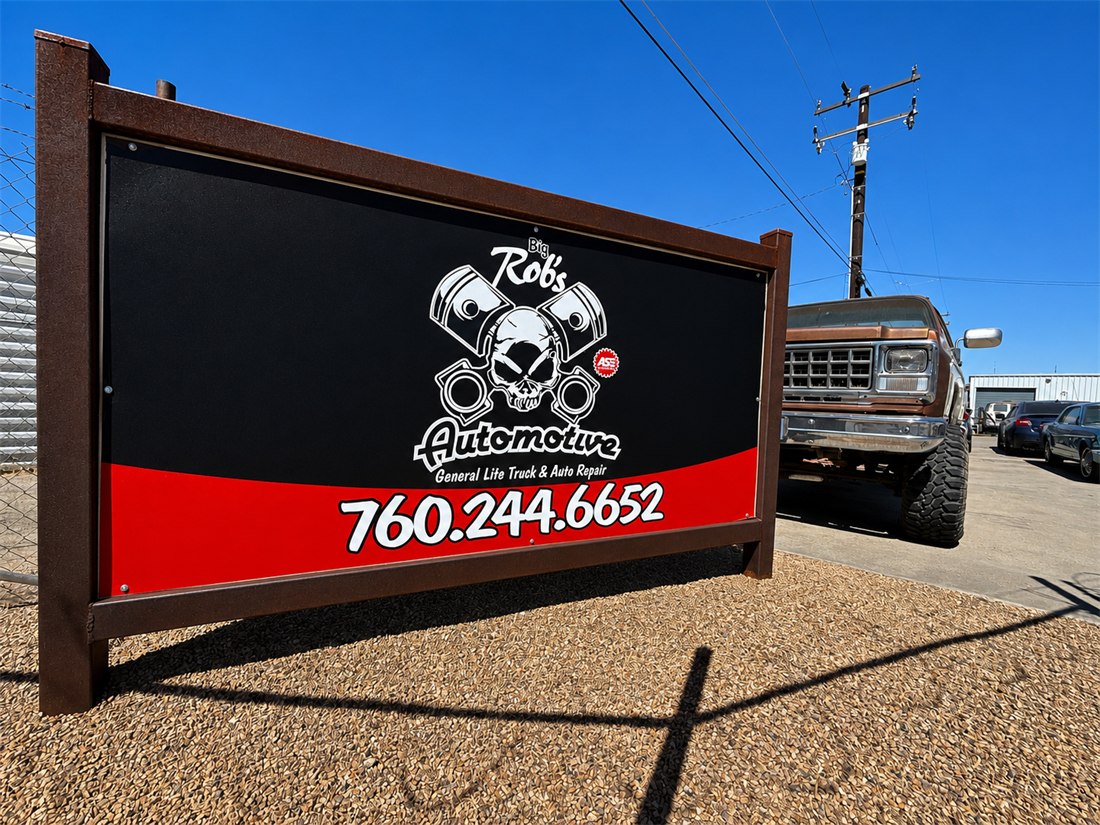 Big Rob's Automotive shop sign — skull-and-pistons logo with phone number 760.244.6652 — with a classic lifted Ford truck parked alongside