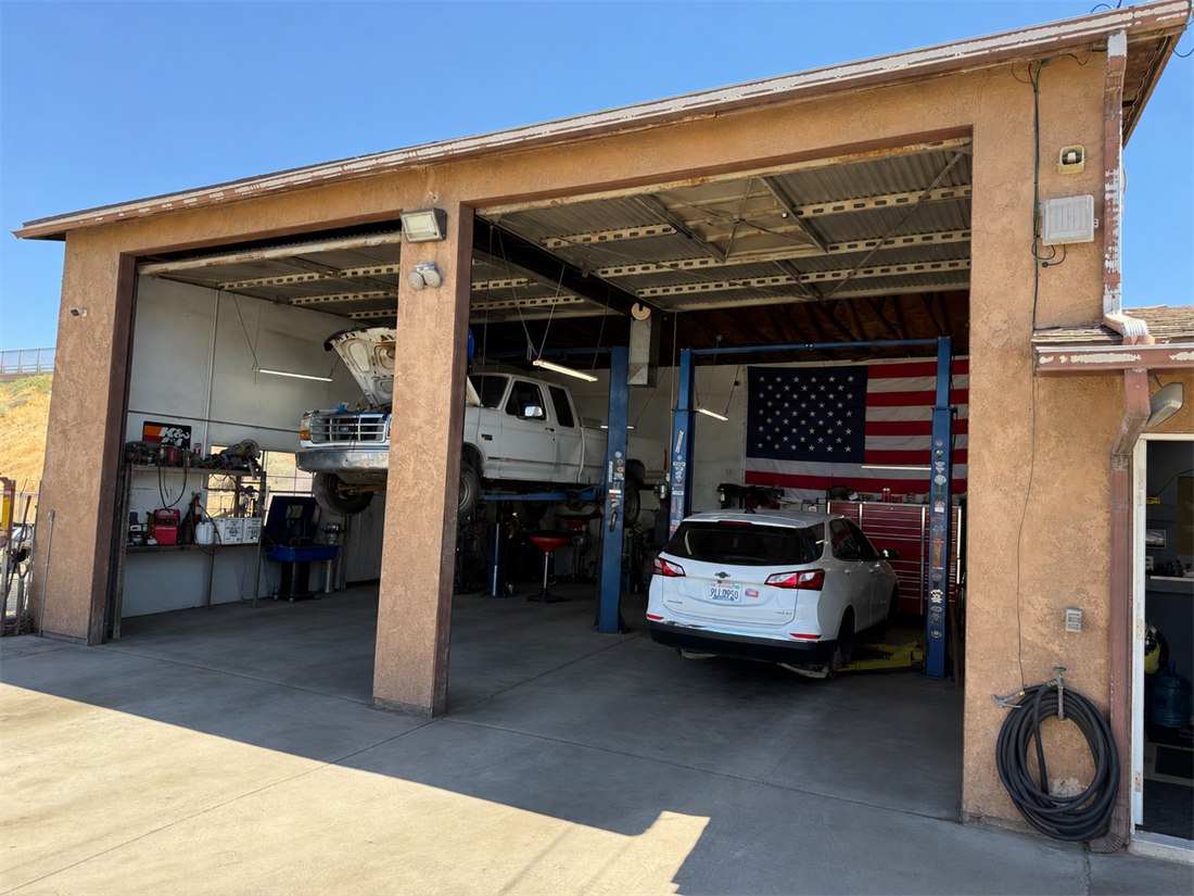 Big Rob's Automotive shop in Hesperia, California — two lift bays with vehicles being serviced and an American flag hanging in the right bay